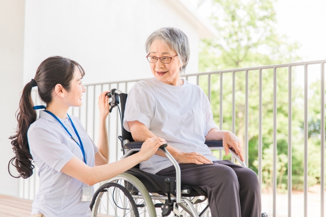 車椅子に座る人の姿勢を介助者が確認している様子